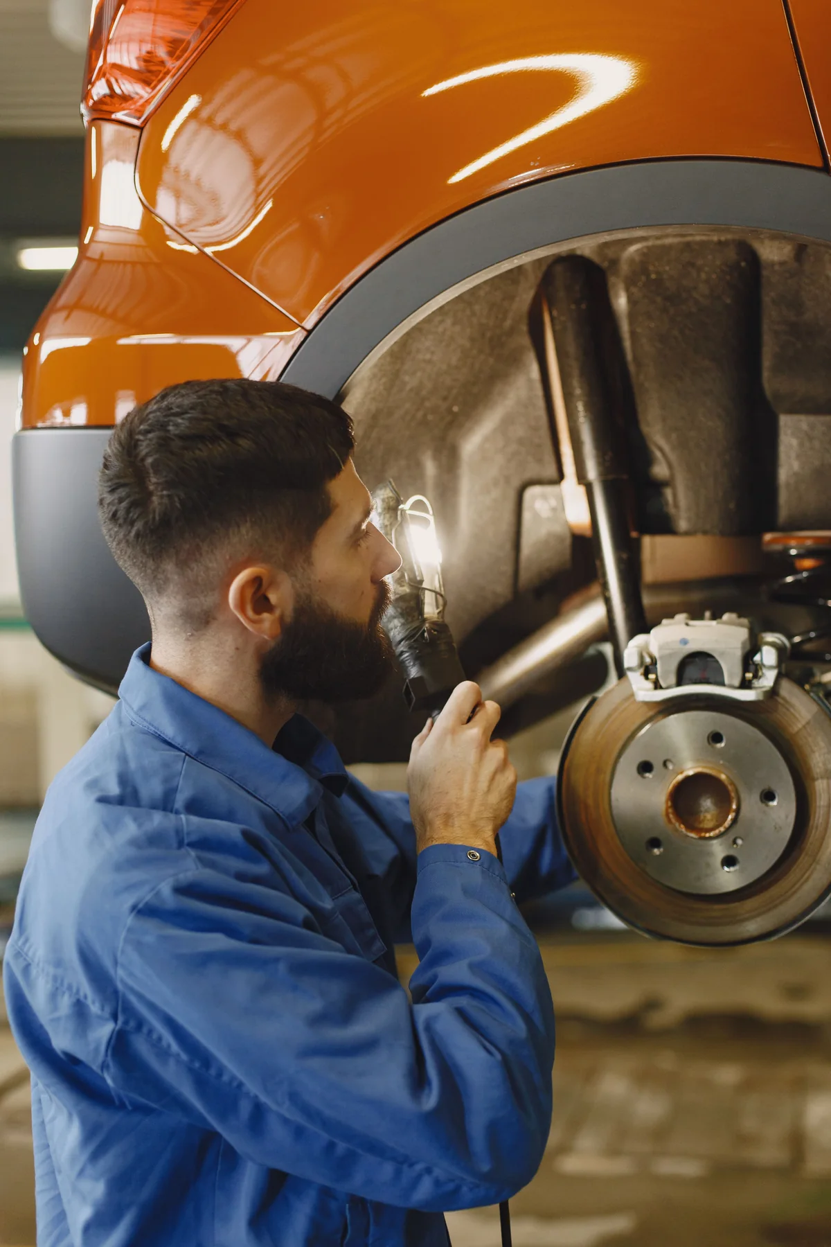 Mechaniker kontrolliert Bremse an einem aufgebockten Fahrzeug