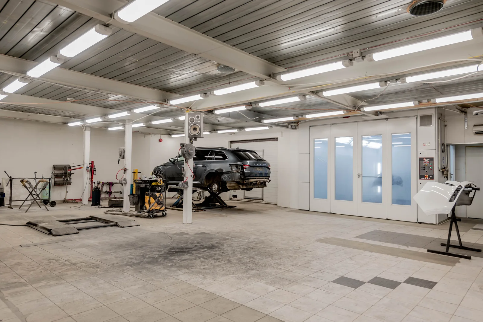 Helle Werkstatt mit mehreren Fahrzeugen auf Arbeitsplätzen